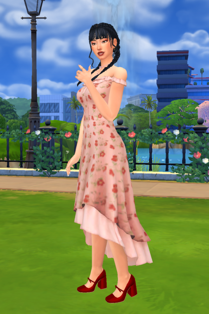 A female Sim wearing a Sims 4 CC outfit stands in a park. She is dressed in a soft pink floral dress, with ruffle accent and a layered skirt. She has a pair of chunky red heels on with a bow.