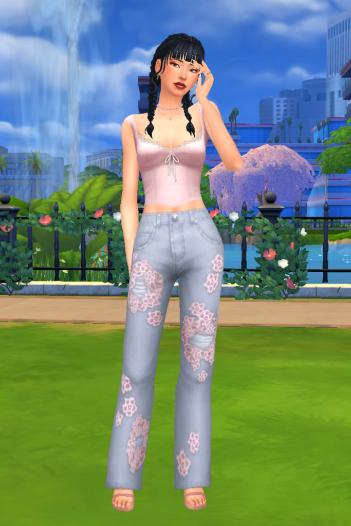 A female Sim wearing a Sims 4 CC outfit stands in a park. She is dressed in a soft pink lace-trim cami top with a front bow and fitted bodice, paired with high-waisted light-wash jeans featuring pink floral lace patch details and distressed accents.