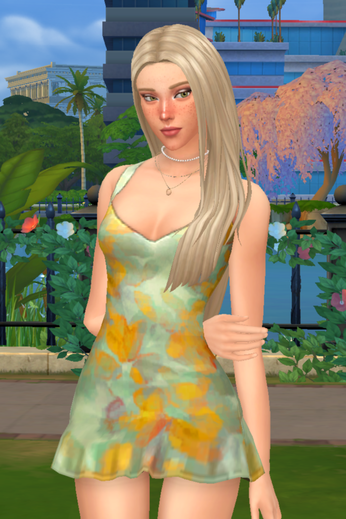 My Favourite Sims 4 CC Mini Dress Finds A blonde female Sim models a Sims 4 CC fit and flare mini dress. The dress has a green and yellow watercolour pattern throughout.