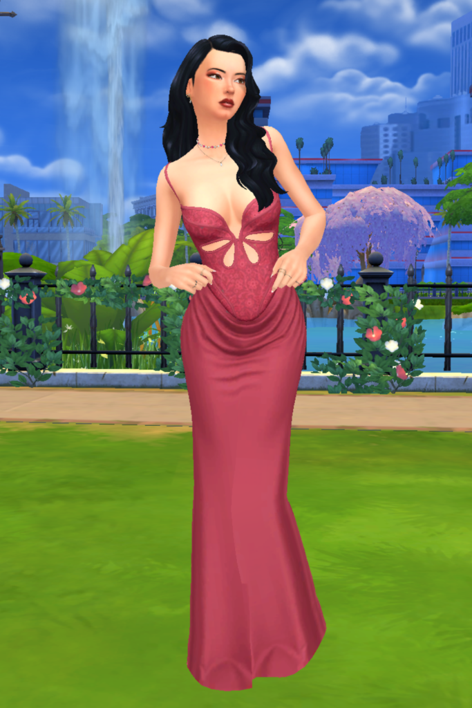 A female Sim wearing a Sims 4 CC outfit stands in a park. She is dressed in an elegant full length dress. The dress is a soft pink colour, with a lacy bodice and petal cutouts along the top.