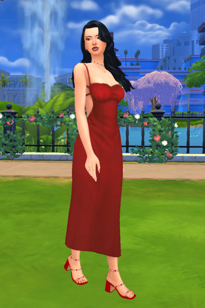 A female Sim wearing a Sims 4 CC outfit stands in a park. She is dressed in an elegant fitted red midi-length dress, with an open back. She has on a pair of strappy red heels with hearts along the straps.